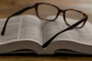 libro aperto su scrivania con occhiali