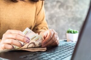 Come posso verificare se ho debiti attivi con le banche 23 mani che contano banconote vicino a laptop