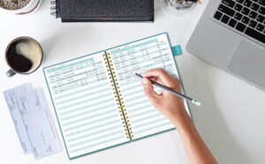 mani che scrivono su un registro contabile