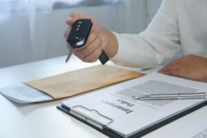 mano che firma contratto assicurativo con chiavi