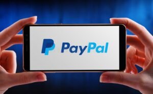 mano che tiene smartphone con logo paypal