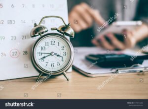 orologio con calendario e dati finanziari sfocati